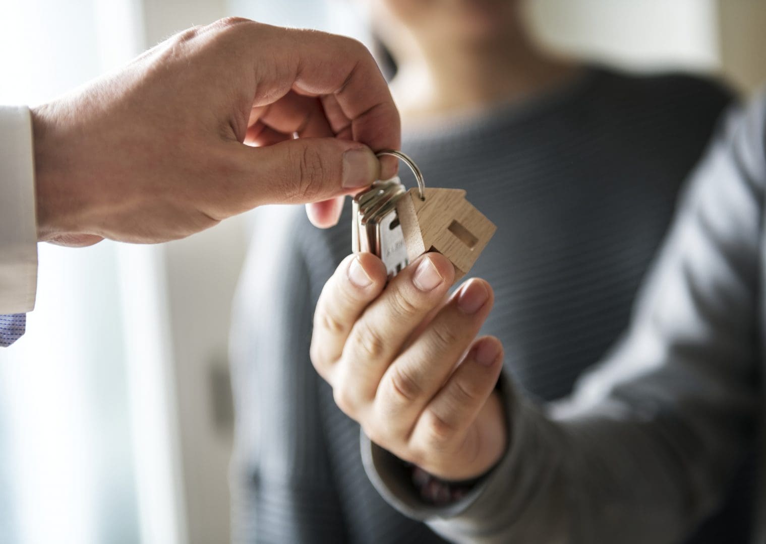 A woman handing a house key to a man.