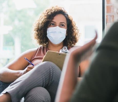A woman wearing a surgical mask is talking to a woman wearing a surgical mask.