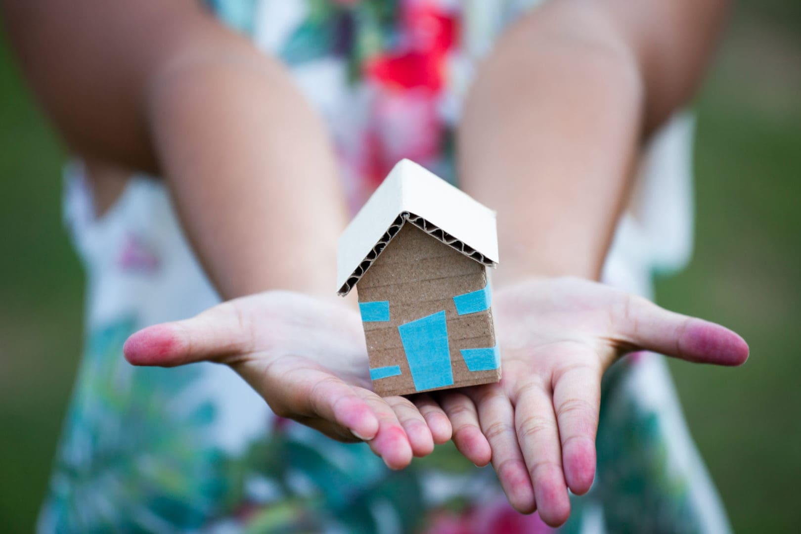 A girl holding a cardboard house in her hands.