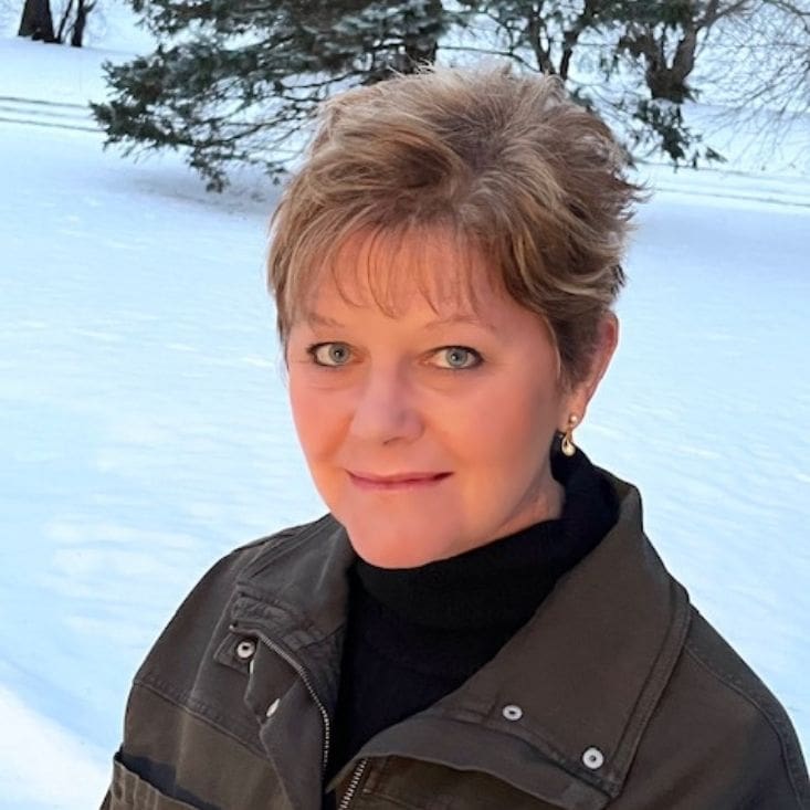A woman in a black jacket standing in the snow.