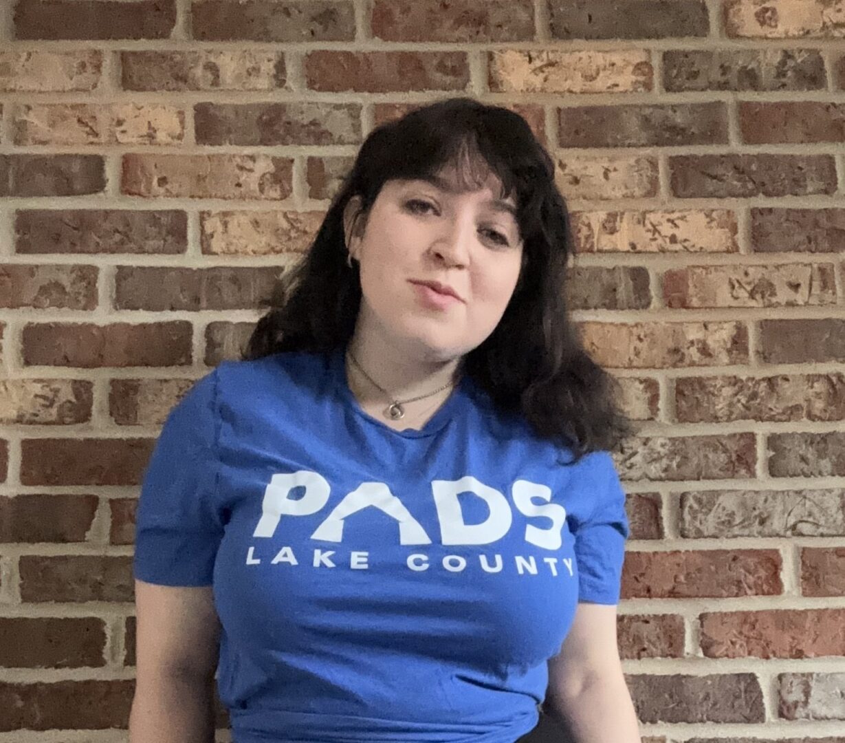 Person in blue shirt with brick background.